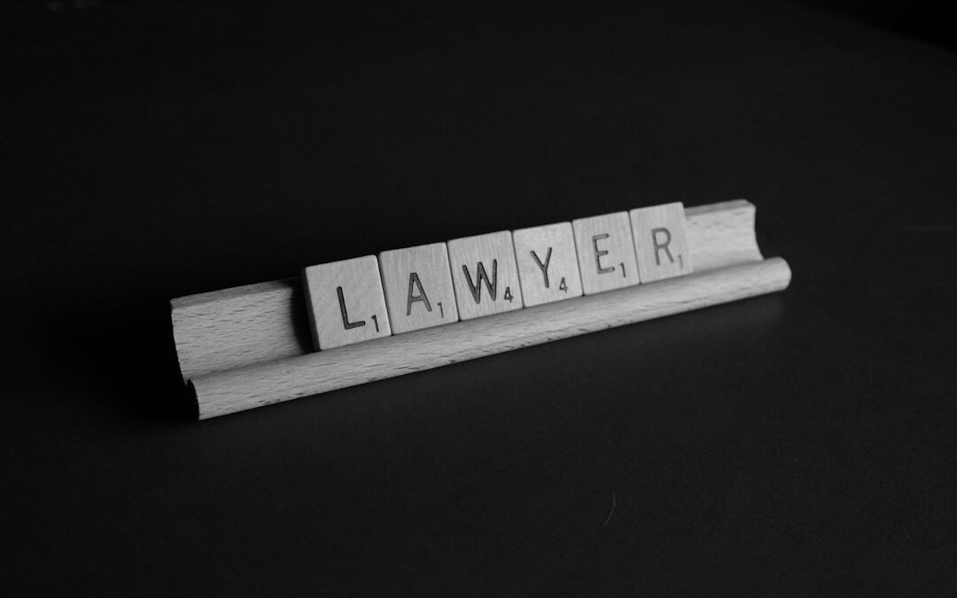 Wooden Scrabble tiles spelling 'LAWYER' on a dark surface.