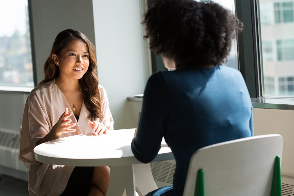 Two people sitting at a round table in an office setting, engaged in conversation.